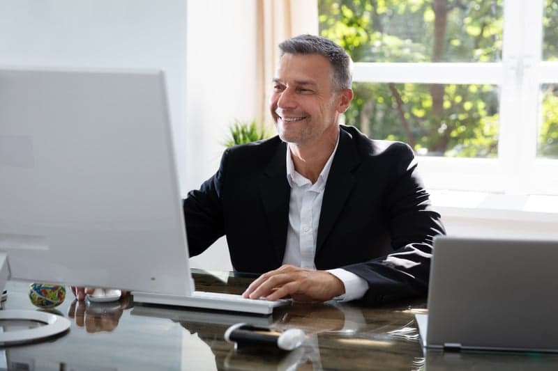 A professional working at a desktop computer in a bright office with garden views